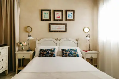 a bedroom with a white bed with two tables and two lamps at innCádizPalacio Apolo in Cádiz