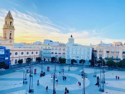 a group of people walking around a plaza in a city at innCádizPalacio Apolo in Cádiz