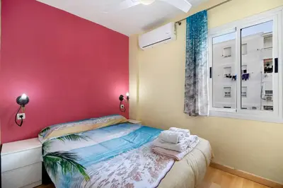 a small bedroom with a pink wall and a bed at La Gaviota in Rota