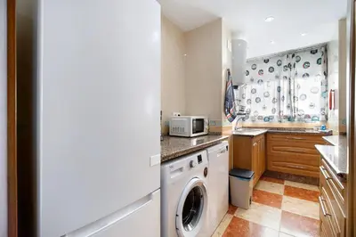 a kitchen with a washing machine and a microwave at La Gaviota in Rota