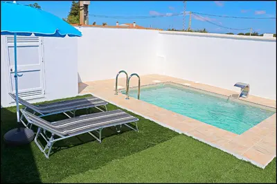 a swimming pool with a chair and an umbrella at Chalet los Morenos in Conil de la Frontera