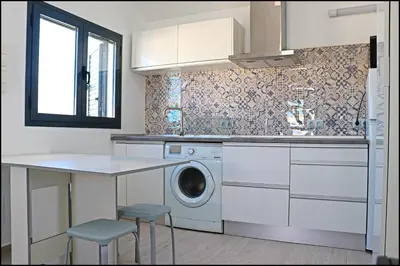 a kitchen with a washing machine and a table at Chalet los Morenos in Conil de la Frontera