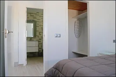 a bedroom with a bed and a bathroom with a sink at Chalet los Morenos in Conil de la Frontera