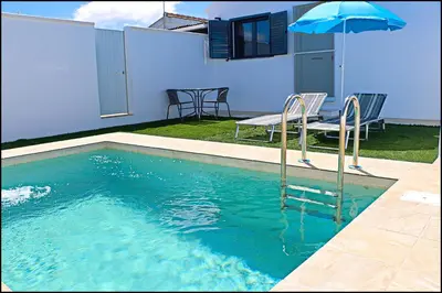 a swimming pool with a table and an umbrella at Chalet los Morenos in Conil de la Frontera