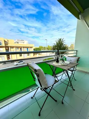 a balcony with a table and chairs and a green screen at GATU Villa Sol, junto a la playa , piscina, 2 baños, aire cc, terraza, 