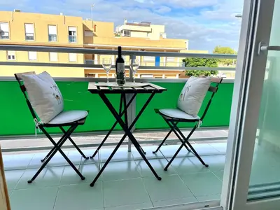 two chairs and a table on a balcony with a bottle of wine at GATU Villa Sol, junto a la playa , piscina, 2 baños, aire cc, terraza, 