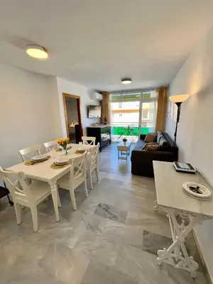a living room with a table and chairs and a couch at GATU Villa Sol, junto a la playa , piscina, 2 baños, aire cc, terraza, 