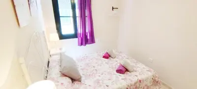 a bedroom with a bed with pink sheets and pillows at Apartamento Tres Carabelas II, AC, Wifi, Parking in Sanlúcar de Barrameda