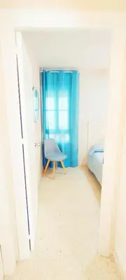 a room with a blue chair and a bed at Apartamento Tres Carabelas II, AC, Wifi, Parking in Sanlúcar de Barrameda