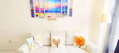 a white couch with pillows and a painting on the wall at Apartamento Tres Carabelas II, AC, Wifi, Parking in Sanlúcar de Barrameda