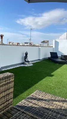 a yard with green grass and a white wall at Ático centro in El Puerto de Santa María