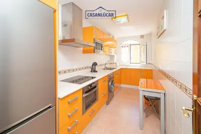 a kitchen with orange cabinets and a stove top oven at Apartamento la Infanta in Sanlúcar de Barrameda