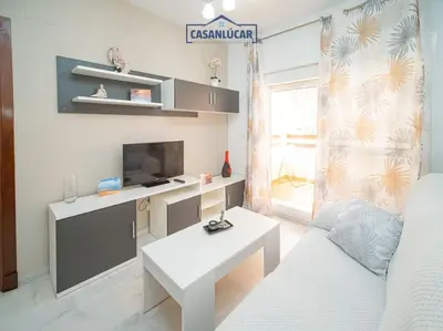 a living room with a white couch and a table at Apartamento la Infanta in Sanlúcar de Barrameda