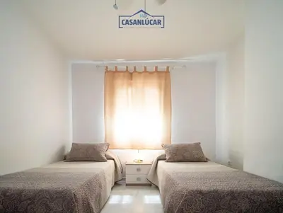 two beds in a room with a window at Apartamento la Infanta in Sanlúcar de Barrameda