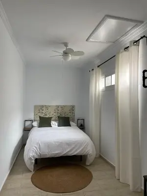 a white bedroom with a bed and a ceiling fan at Dúplex Céntrico perfecto para el disfrute in El Puerto de Santa María