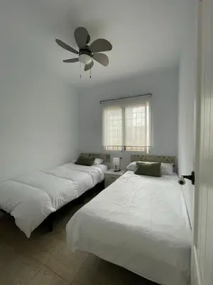 two beds in a room with a ceiling fan at Dúplex Céntrico perfecto para el disfrute in El Puerto de Santa María