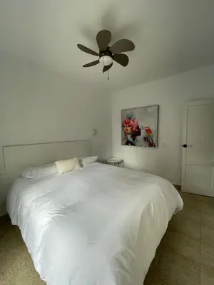 a bedroom with a white bed with a ceiling fan at Dúplex Céntrico perfecto para el disfrute in El Puerto de Santa María
