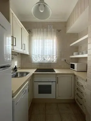 a kitchen with white cabinets and a sink and a window at Dúplex Céntrico perfecto para el disfrute in El Puerto de Santa María