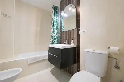 a bathroom with a toilet and a sink and a mirror at Atico Costa Doñana in Bonanza