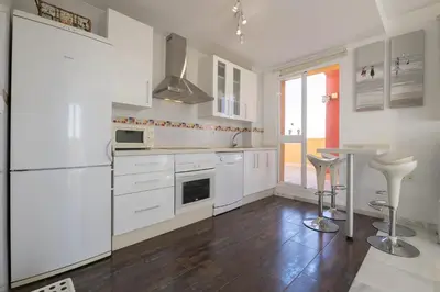 a white kitchen with white appliances and a table at Atico Costa Doñana in Bonanza