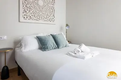 a bedroom with a white bed with blue pillows at Writer's Home by Cadiz Time in Cádiz