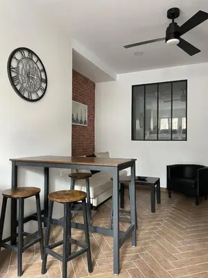 a dining room with a table and stools and a clock at Piso Céntrico perfecto para hospedarse in El Puerto de Santa María