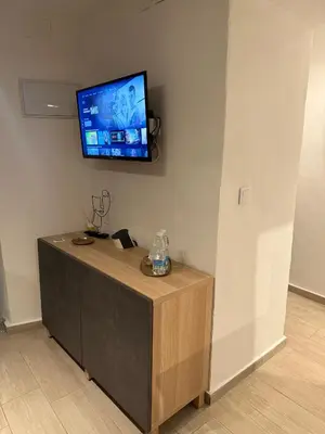 a flat screen tv on a wall with a wooden cabinet at La Faraona in Jerez de la Frontera