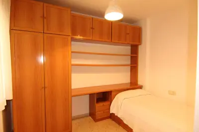 a bedroom with a bed and a wooden closet at Apartamento Paola in El Puerto de Santa María