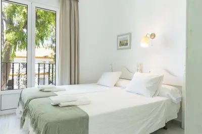 two beds in a white room with a window at Playa de Regla, para un magnifico descanso. 3. in Chipiona