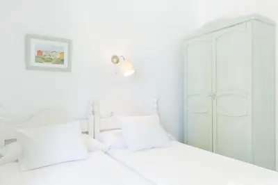 a white bedroom with a bed and a cabinet at Playa de Regla, para un magnifico descanso. 3. in Chipiona