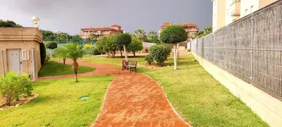a park with a bench and trees and a fence at Apartamento TomCar Piscina, Pádel, wifi y zonas comunes in Sanlúcar de Barrameda