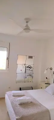 a white bedroom with two beds and a ceiling at Apartamento TomCar Piscina, Pádel, wifi y zonas comunes in Sanlúcar de Barrameda