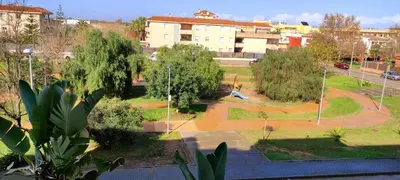 a view of a park with trees and a building at Apartamento TomCar Piscina, Pádel, wifi y zonas comunes in Sanlúcar de Barrameda
