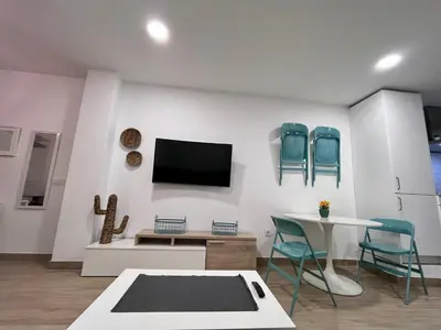 a living room with a tv and a table and chairs at GATU Villa Paraguay in Cádiz