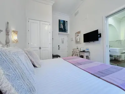 a white bedroom with a large bed and a sink at Hotel Boutique Las Cortes De Cádiz in Cádiz