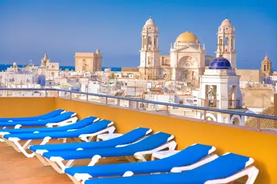 a row of chaise lounge chairs on a balcony overlooking the city at Senator Cádiz in Cádiz