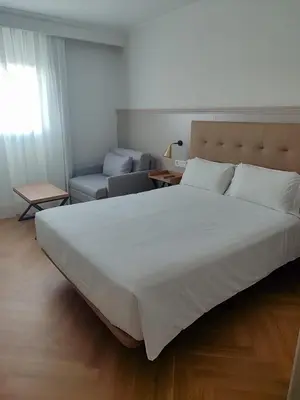 a bedroom with a large white bed with two night stands at Senator Cádiz in Cádiz