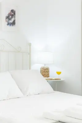 a white bedroom with a white bed and a side table at Apartamento independiente en Playa de Regla. in Chipiona