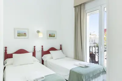two beds in a room with a window at Amplio apartamento en Playa de Regla. 2. in Chipiona