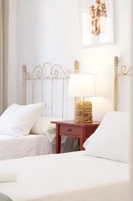 a bedroom with two beds and a table with a lamp at Amplio apartamento en Playa de Regla. 2. in Chipiona