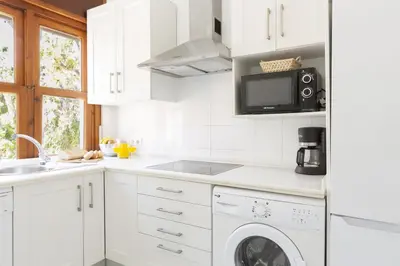 a kitchen with white cabinets and a washer and dryer at Amplio apartamento en Playa de Regla. 2. in Chipiona