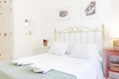 a white bedroom with a bed with white sheets and pillows at Amplio apartamento en Playa de Regla. 2. in Chipiona