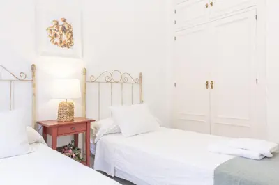 a bedroom with two beds and a table with a lamp at Amplio apartamento en Playa de Regla. 2. in Chipiona