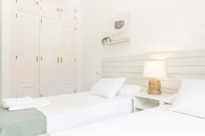 two beds in a bedroom with white walls at Apartamento coqueto en la Playa de Regla. 4. in Chipiona