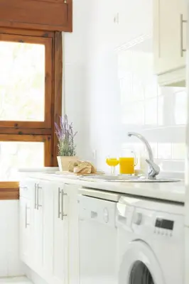 a white kitchen with a sink and a washing machine at Apartamento coqueto en la Playa de Regla. 4. in Chipiona