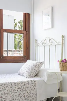 a white bed with a pillow and a table at Apartamento coqueto en la Playa de Regla. 4. in Chipiona