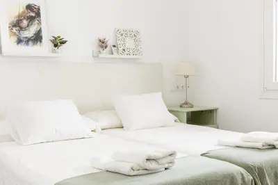 two beds in a white room with towels on them at Precioso apartamento con Chimenea patio solarium. in Chipiona