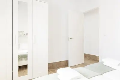 a white bedroom with white wardrobes at Precioso apartamento con Chimenea patio solarium. in Chipiona
