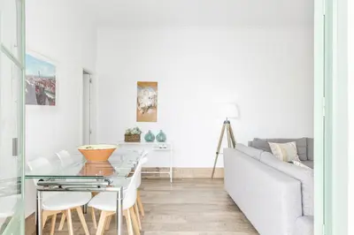 a white living room with a table and a couch at Precioso apartamento con Chimenea patio solarium. in Chipiona