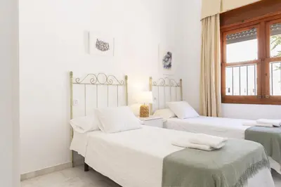 two beds in a room with white walls at Apartamento Playa de Regla con terraza. 1. in Chipiona